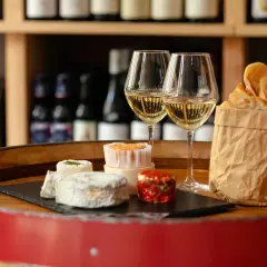 Dégustation de fromages et de pain frais avec deux verres de vin blanc, une scène parfaite pour un vin Paris.