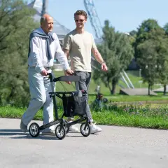 Ein älterer Mann geht mit einem Rollator spazieren, der ihm Halt gibt. Es gibt verschiedene Gehhilfen, die Mobilität im Alter unterstützen.