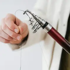 Dłoń trzymająca żyłkę przy końcu wędki z przelotkami.