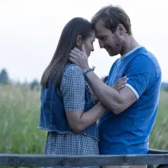 Para przytula się na tle łąki. Ich czoła się stykają, a spojrzenia są pełne czułości. To chwila, gdy wszystko dzieje się **nic na siłę**.