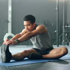 Mann dehnt sich im Fitnessstudio, um den Muskelaufbau zu unterstützen.