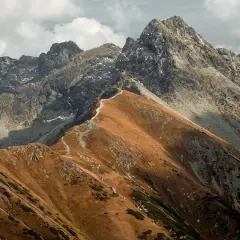 Jesienne, **czerwone wierchy szczyty** Tatr, z kamienistymi zboczami i ścieżką wijącą się po grani.
