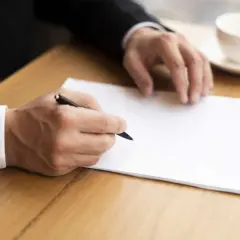 Homme en costume écrivant une lettre. Il pourrait s'agir d'une démarche concernant le harcèlement moral, avec l'aide de la médecine du travail.
