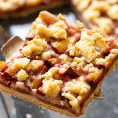 Ein Stück Zwetschgendatschi mit Streuseln wird mit einer Tortengabel herausgehoben. Das Zwetschgendatschi Rezept ist ein Genuss!