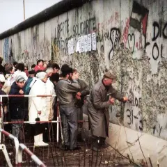 Ludzie przyglądają się i wykuwają napisy na Murze Berlińskim, gdy postawiono mur berliński.