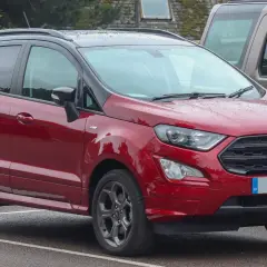 Czerwony Ford EcoSport 2018 z czarnym dachem, zaparkowany na mokrym parkingu.