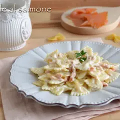 Farfalle al salmone cremose, un piatto invitante con pasta a forma di farfalla e pezzetti di salmone affumicato, guarnito con prezzemolo fresco.