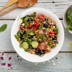 Insalata di quinoa colorata con ceci, pomodorini, olive, cetrioli e rucola. Un piatto fresco e salutare.
