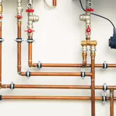 System hydrauliczny z miedzianymi rurami i zaworami. Różnica między złączkami PEX U czy TH jest kluczowa dla szczelności instalacji.