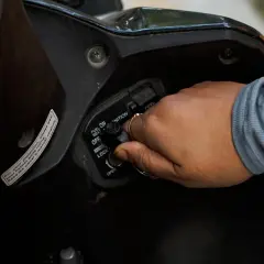 Mano girando la llave de encendido por magneto en una motocicleta.
