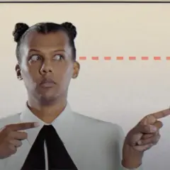 Stromae w Polsce, z charakterystycznymi kucykami, wskazuje na strzałkę.