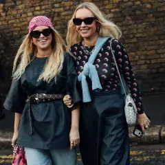 Dos mujeres sonríen, luciendo estilos audaces que anticipan la moda primavera verano 2026.
