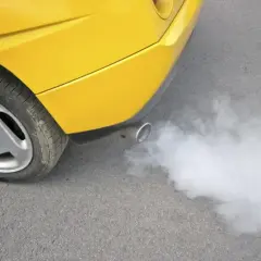 Żółte auto z wydechu pluje białą parą, jakby miało gorączkę.