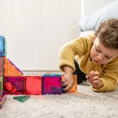 Niño concentrado jugando con bloques magnéticos de colores, ideales para actividades para niños de 2 a 3 años.
