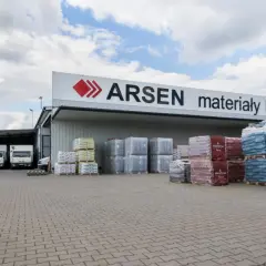 Budynek ARSEN materiały budowlane. Przed magazynem stoją ciężarówki i palety z materiałami. Sprawdź godziny otwarcia!