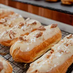 Éclairs dorés sur une grille, nappés d'un glacage sirop d'érable et parsemés de noix concassées. Un délice gourmand.