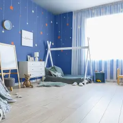 Pokój dziecka z niebieskimi ścianami i gwiazdkami. Inspiracje jak pomalować pokój dziecka: namiot tipi, łóżko domek, tablica, meble i stolik.