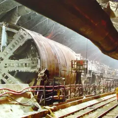 Ogromna tarcza drążąca tunel, budowa eurotunelu. Pracownicy nadzorują postęp prac w podziemnym korytarzu.