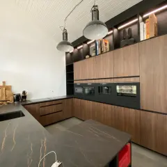 Un plan de cuisine moderne avec des armoires en bois, un îlot en marbre noir et des appareils intégrés.