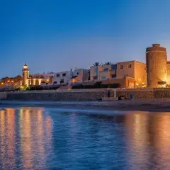 Atardecer en Roquetas de Mar. Faro y castillo iluminados, reflejos en el mar. ¡Ideas de qué hacer en Roquetas de Mar!