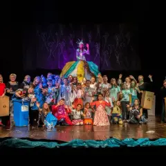 Uczestnicy studia teatralnego Gorzów pozują na scenie z kolorowymi strojami i koszami do segregacji śmieci.