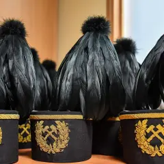 Czako górnicze z czarnymi piórami i złotym haftem młota i kilofa.