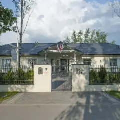 Elegancki lawendowy dom opieki seniora, z pięknym ogrodem i bramą.