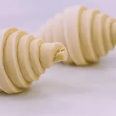 Dos croissants de mantequilla crudos, con sus capas visibles, listos para hornearse y deleitar.