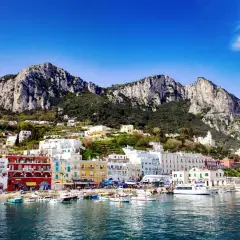 Kolorowe domy nad zatoką, góry w tle. Widok na urokliwy port na wyspie Capri.