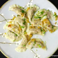 Pyszne pierogi z kaszą gryczaną bez sera, okraszone cebulką i posypane natką pietruszki.