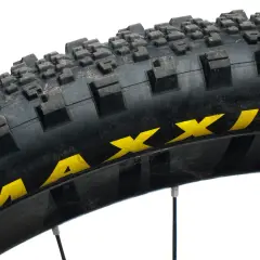 Close-up of a Maxxis Minion SS tire, showing its aggressive tread pattern and yellow branding. Ready for any trail.