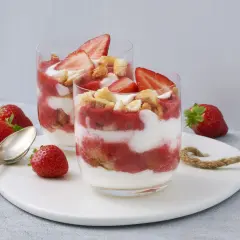 Zwei Gläser mit einem sommerlichen Dessert aus Erdbeeren und Sahne, garniert mit frischen Erdbeerscheiben und Keksstückchen. Ein schnell und einfach zubereitetes Genusserlebnis.