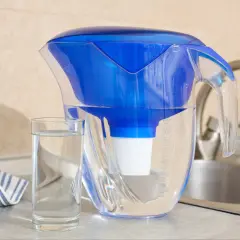 Dzbanek filtrujący wodę, szklanka czystej wody i ręcznik. Dbanie o czystą wodę to walka z mikroplastikiem w wodzie.
