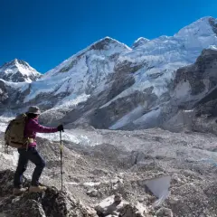 Turystka z plecakiem i kijkami trekkingowymi podziwia majestatyczne szczyty Himalajów w drodze do Everest Base Camp.
