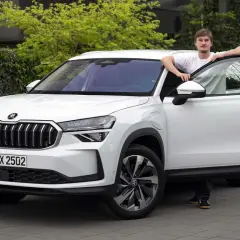 En ung man lutar sig mot en vit Skoda Kodiaq med öppen dörr. En spännande skoda kodiaq test.