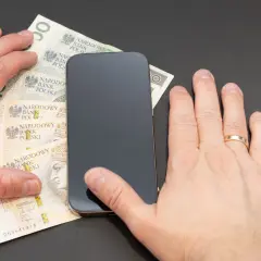 Dłonie przy smartfonie i polskich banknotach. Czy można cofnąć blik?