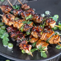 Leckeres Yakitori: saftige Hähnchenspieße mit Teriyaki-Glasur, garniert mit Sesam und Frühlingszwiebeln.