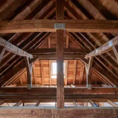 Vue d'une charpente en bois avec des renforts métalliques, suggérant un renfort panne charpente pour assurer la solidité.
