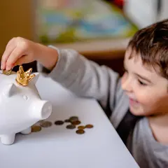 Chłopiec wrzuca monetę do świnki skarbonki. Zastanawiasz się, ile kosztuje adwokat w sprawie o podwyższenie alimentów?
