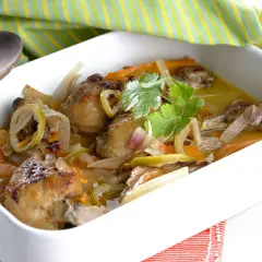 Muslitos de pollo guisados con verduras y limón, servidos en una cazuela blanca.