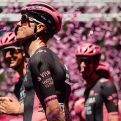 Kolarze w różowych kaskach i strojach świętują sukces na Criterium du Dauphiné, zasypani konfetti.