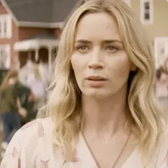 Emily Blunt i en scen från filmer med emily blunt. Hon ser orolig ut medan folk rör sig i bakgrunden.