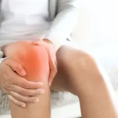 Person hält schmerzendes Knie, das rot leuchtet. Richtige Schuhe können bei Knieschmerzen helfen.