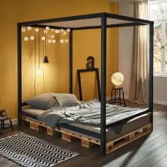 Ein modernes Himmelbett, das man leicht selber bauen kann, mit Paletten als Basis. Lichterketten und eine gelbe Wand schaffen Gemütlichkeit.