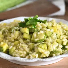 Un cremoso risotto con zucchine fresche, cotto in padella e guarnito con prezzemolo. Un piatto leggero e saporito.