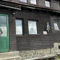 Kobieta w kasku rowerowym zbliża się do drzwi schroniska Chatka Górzystów.