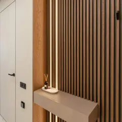 Drewniane lamele i subtelne podświetlenie tworzą tani pomysł na ścianę. Minimalistyczna konsola z dyfuzorem dodaje elegancji.