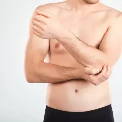 Mężczyzna trzyma się za łokieć, być może wykonuje test cozena.