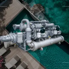Un potente chiller industrial, con su compleja red de tuberías y compresores, se asoma sobre una piscina de aguas cristalinas, evocando frescura y eficiencia.