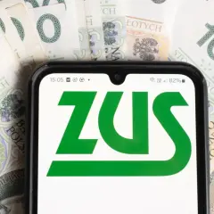 Telefon z logo ZUS na tle banknotów 100 zł. Dowiedz się, komu przysługuje dodatek pielęgnacyjny z ZUS.
